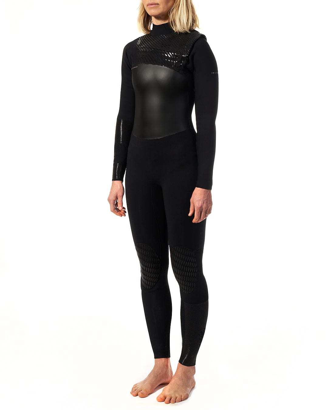 A woman is standing in front of a white background in a Saltrock Shockwave - Womens 3/2 Front Zip Full Wetsuit - Black.