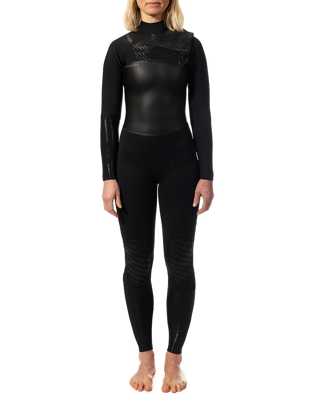 A woman in a Saltrock Shockwave - Womens 3/2 Front Zip Full Wetsuit - Black standing in front of a white background.