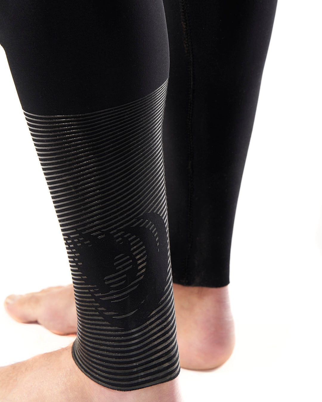 The leg of a man wearing a pair of Shockwave - Mens 3/2 Chest Zip Full Wetsuit - Black leggings by Saltrock.
