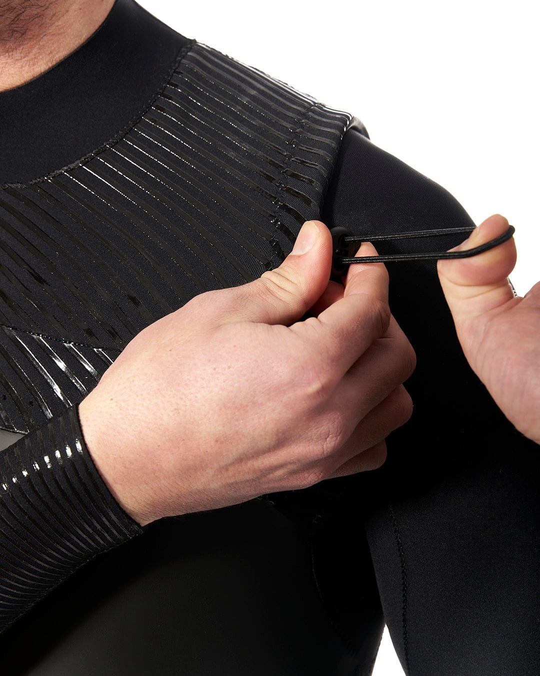 A man is putting on a Shockwave - Mens 3/2 Chest Zip Full Wetsuit - Black wetsuit by Saltrock.