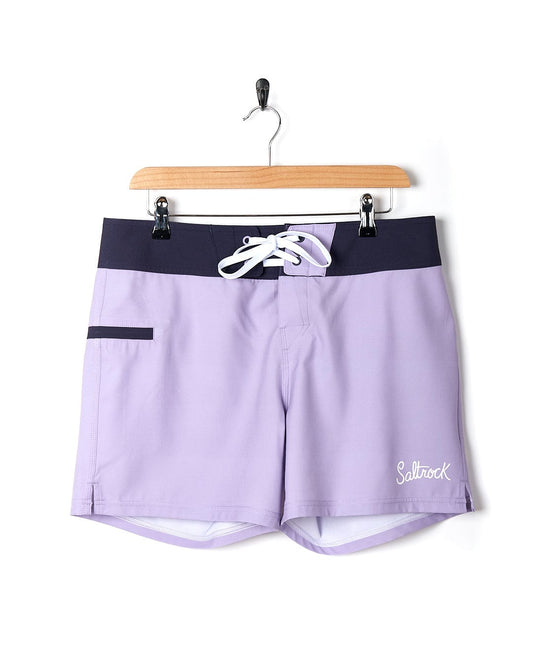 A Saltrock Shoreline Women's Boardshort in Light Purple on a hanger.