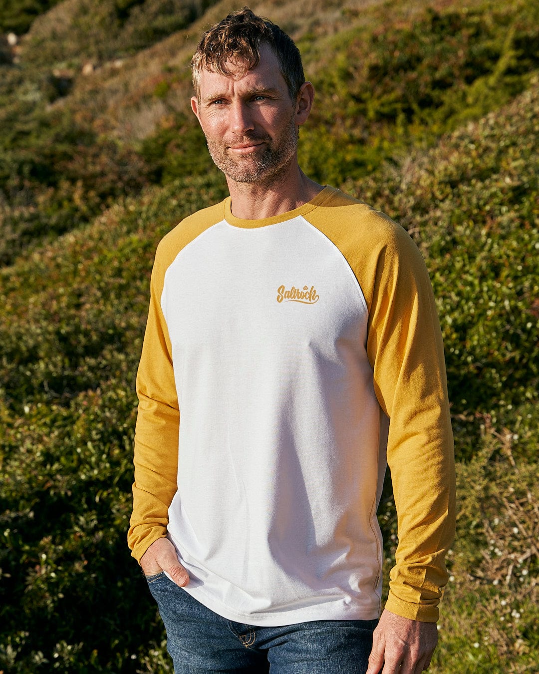 A man wearing a Saltrock Speed - Mens Long Sleeve Raglan T-Shirt - Ochre/White.