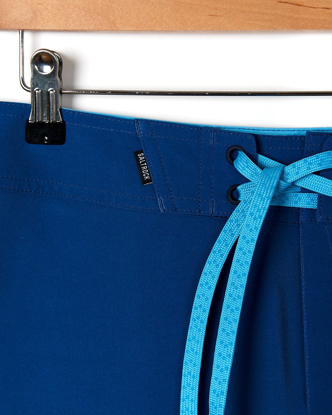 A pair of Splash Gradient - Mens Boardshort - Dark Blue by Saltrock hanging on a hanger.