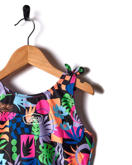 A colorful Sunny Zephyr swimsuit in a black print hangs on a hanger. (Brand: Saltrock)