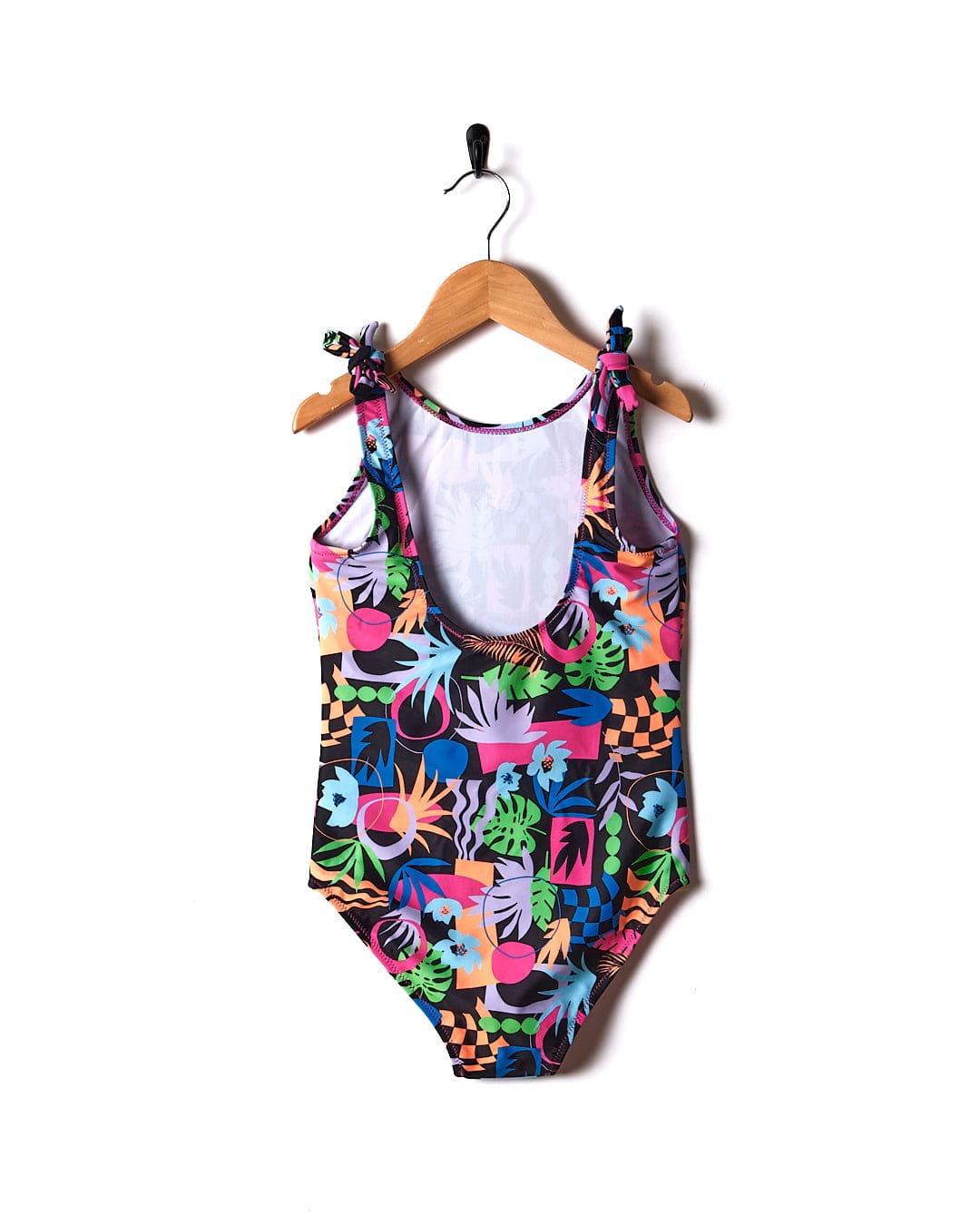 A colorful Sunny Zephyr one piece swimsuit hanging on a wooden hanger.