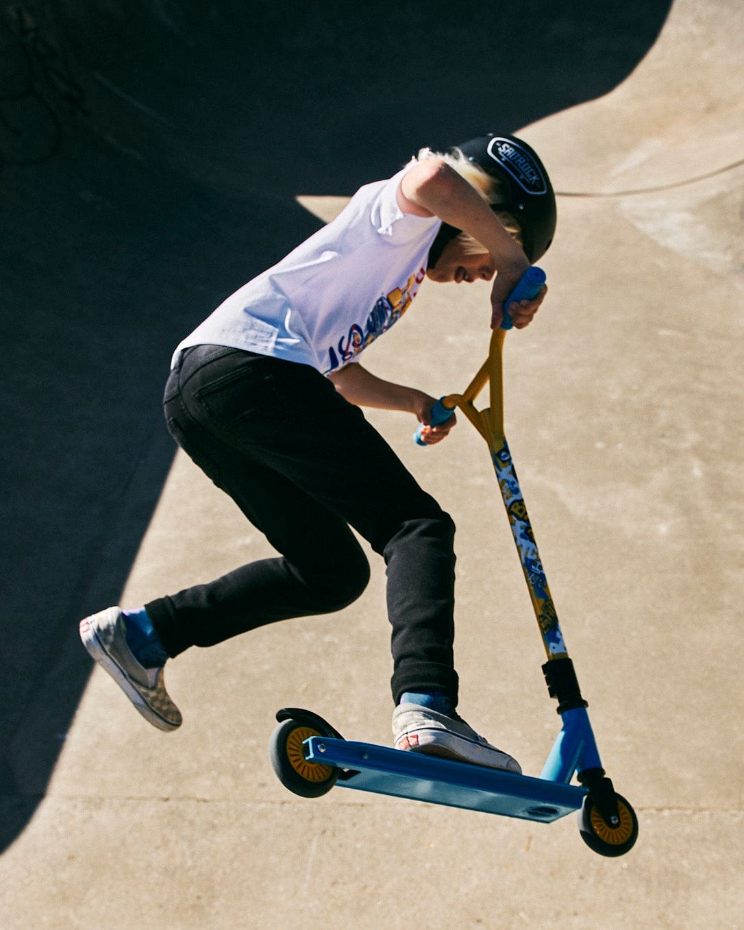 A person riding a Saltrock Warped - Stunt Scooter - Blue in a skate park.