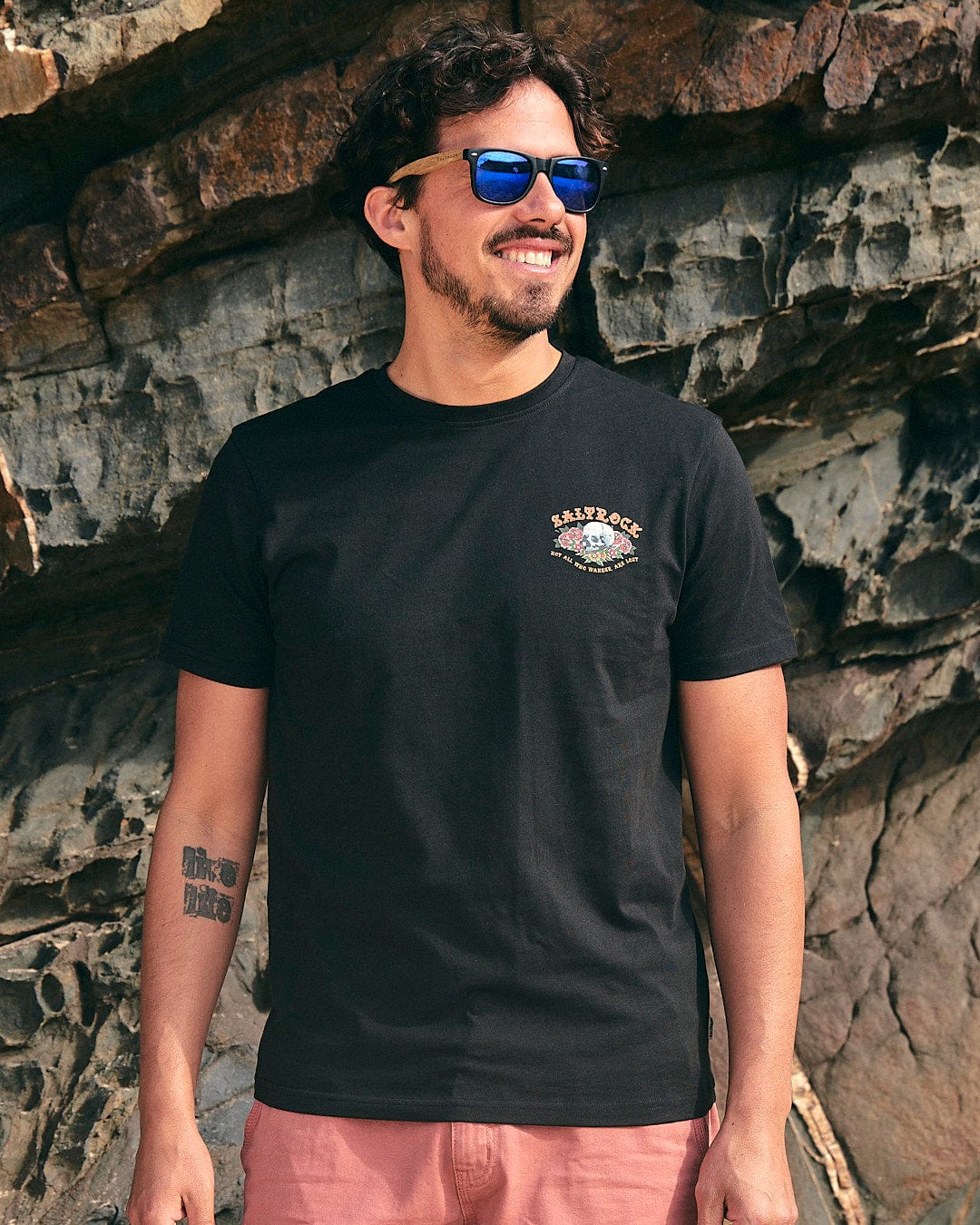 A man wearing a Saltrock Tattoo Island - Mens Short Sleeve T-Shirt - Black and sunglasses.