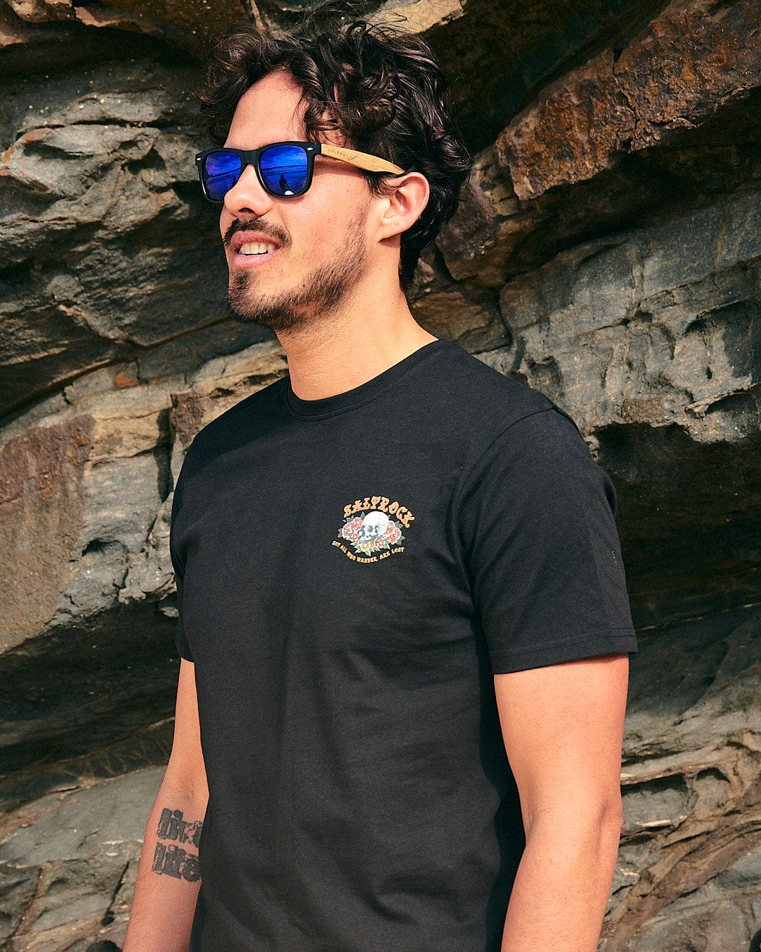 A man wearing sunglasses and a Saltrock - Tattoo Island Mens Short Sleeve T-Shirt - Black.