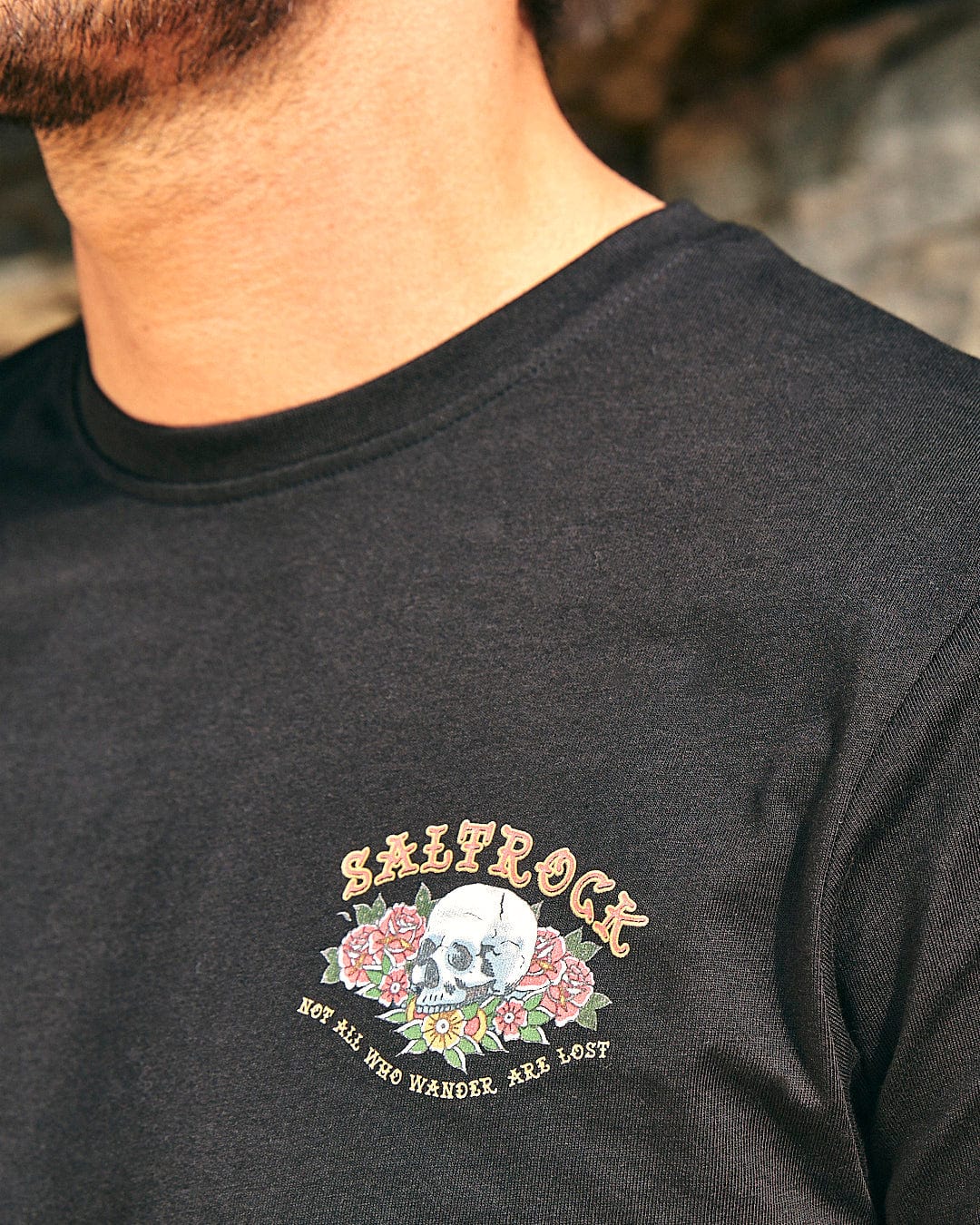 A man wearing a Saltrock Tattoo Island - Mens Short Sleeve T-Shirt - Black with roses on it.