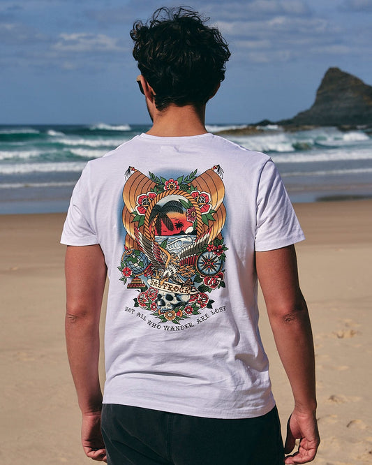A man standing on the beach wearing a Tattoo Island - Mens Short Sleeve T-Shirt in White by Saltrock.