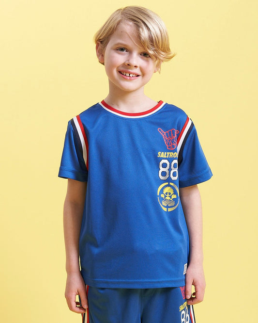 A young boy wearing a Saltrock Team - Kids Short Sleeve T-Shirt - Blue and shorts.