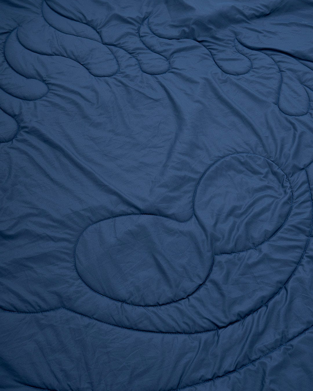 A Yogi - Camping Blanket - Blue quilt on a bed. (Brand: Saltrock)
