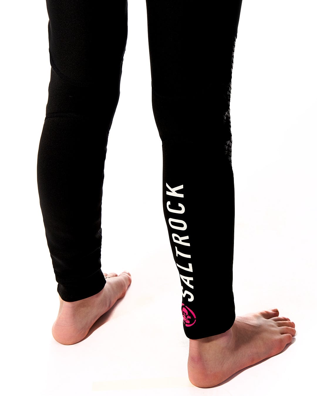 A woman wearing a pair of Zephyr - Kids 3/2 Full Wetsuit - Black leggings with a pink Saltrock logo.