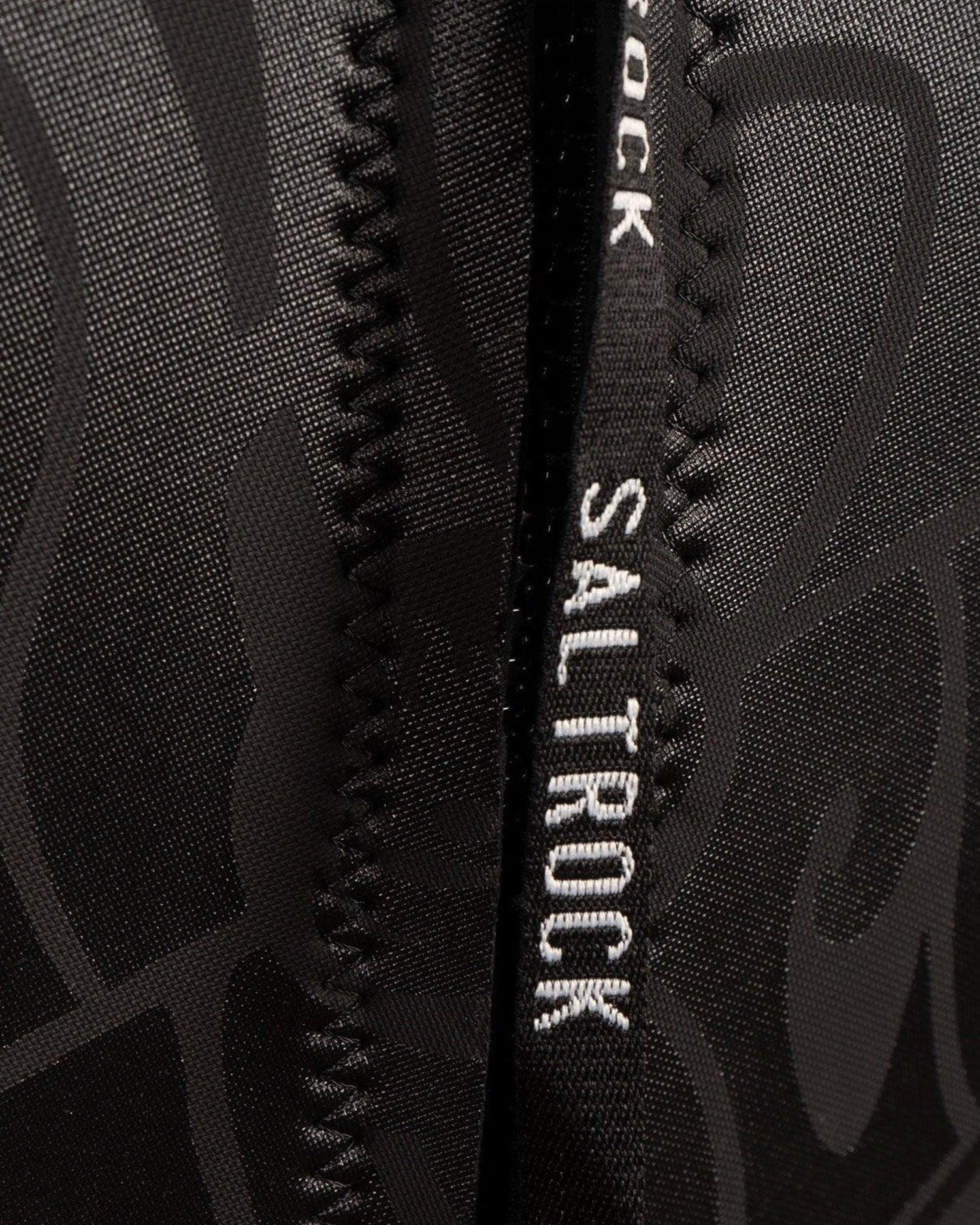 Close-up of a black neoprene Saltrock backpack fabric detail, showing textured patterns and a YKK zipper seam.